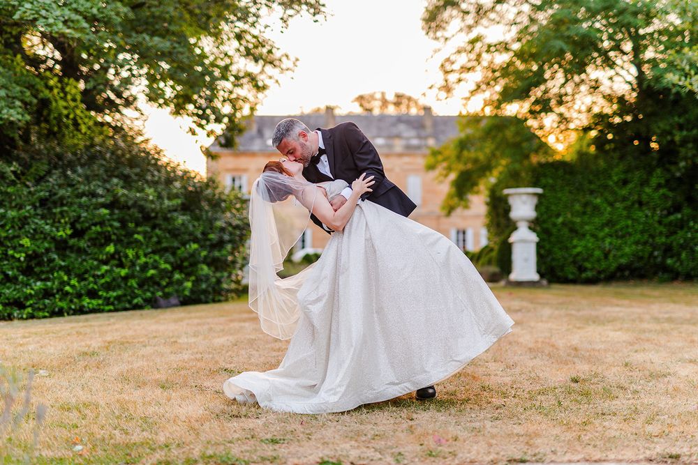 Wedding couple sits together on stone steps surrounded by lush greenery at sunset.