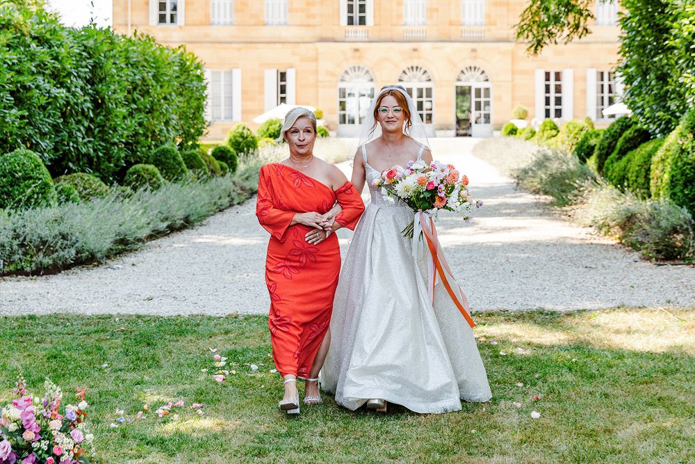 Outdoor garden party setup with chairs and decorations in front of a historic French-style manor house.