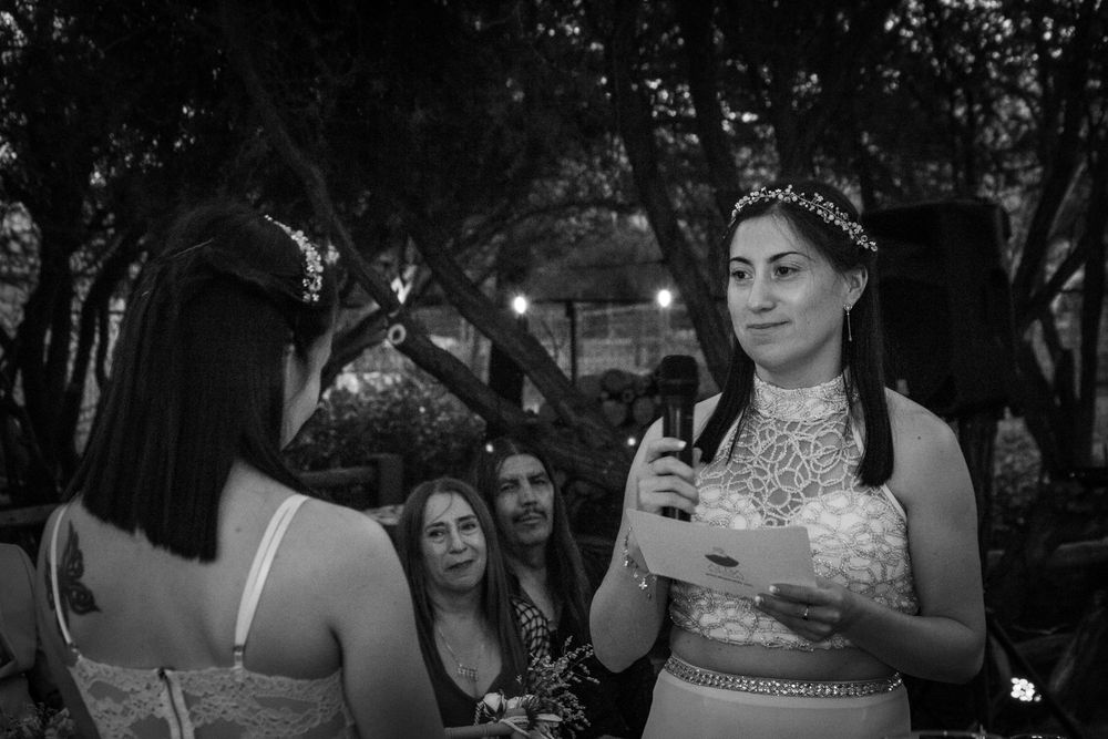 Novia leyendo sus votos matrimoniales con un micrófono y libreta en mano fotografía en blanco y negro durante la ceremonia.