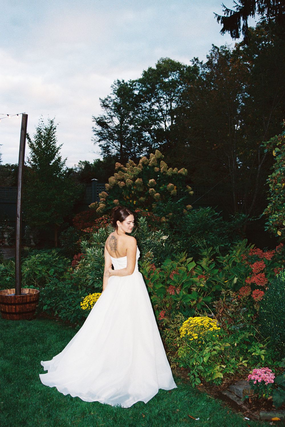 White wedding gown flowing in a garden setting with colorful flowers and greenery.