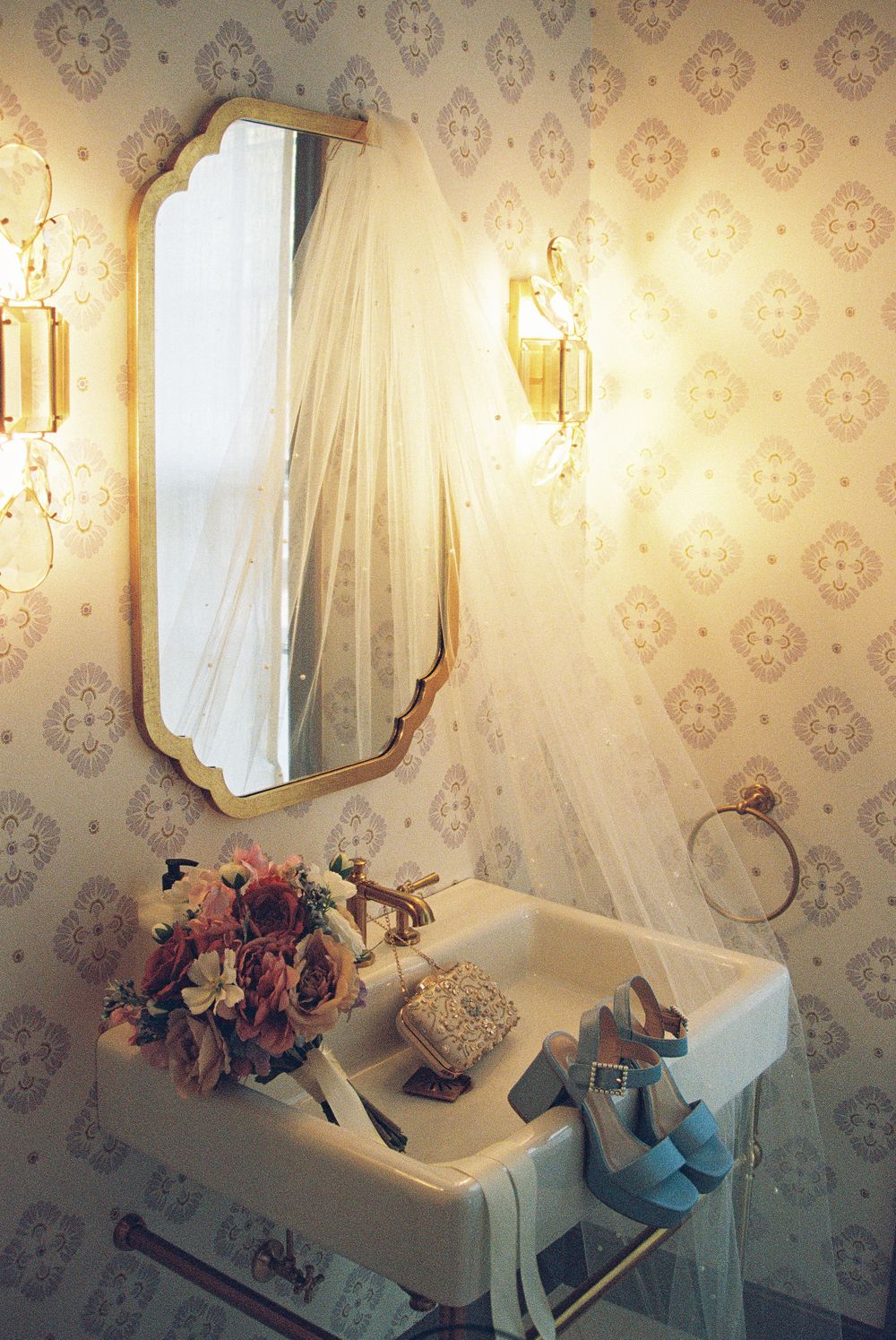 Elegant bridal preparation room with floral wallpaper, mirrors, and flowing white veils.