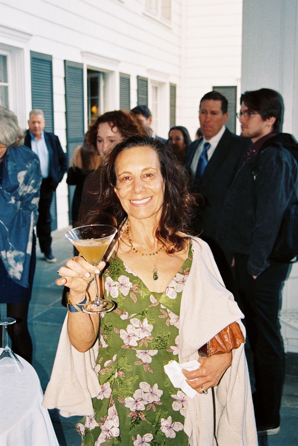 A festive gathering on a porch with people mingling in casual attire.