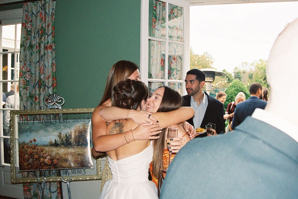 Wedding guests celebrate with champagne toasts in a room with turquoise walls and floral curtains.