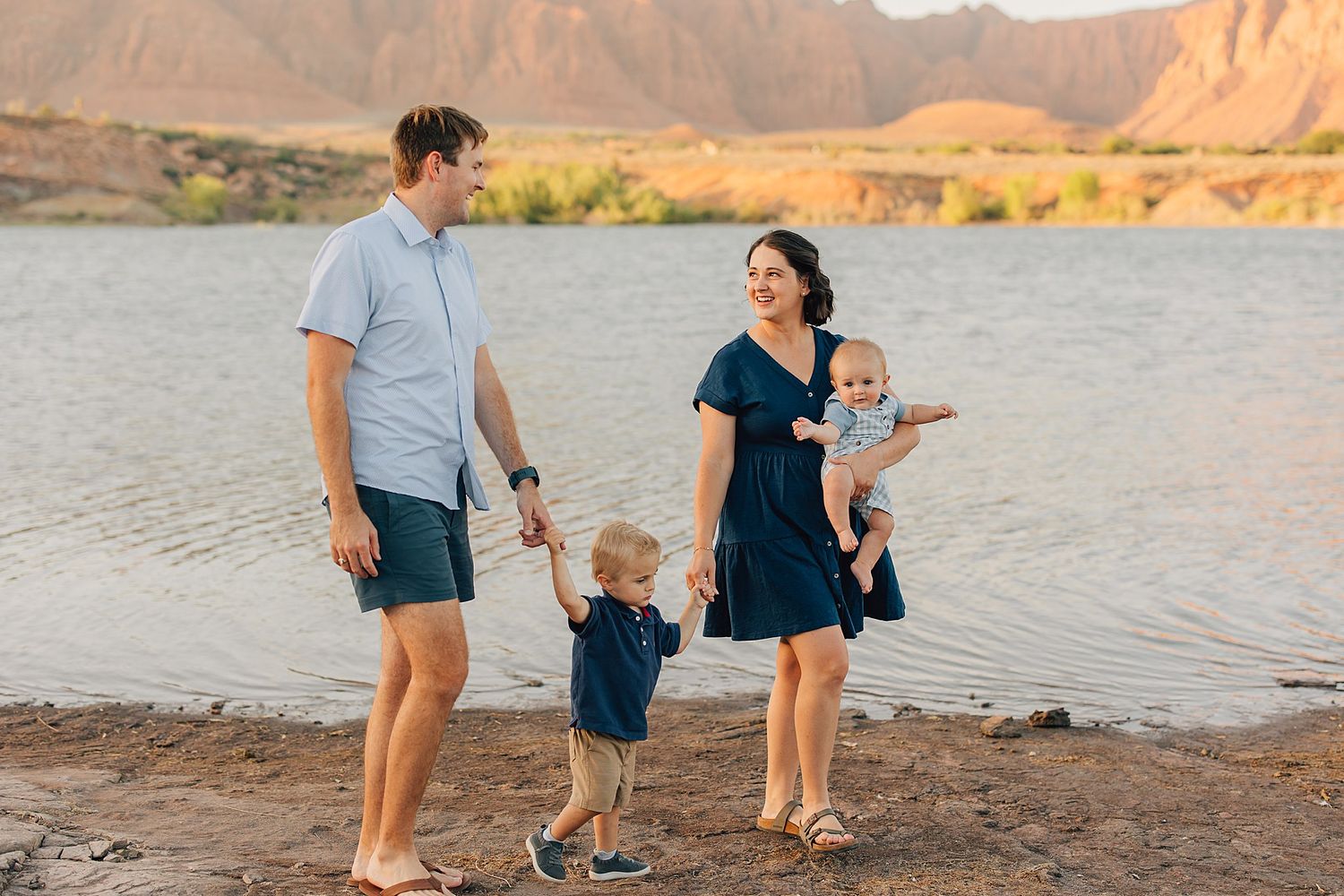 Family of four enjoying a sunny day by a lake with red rock mountains in the background.