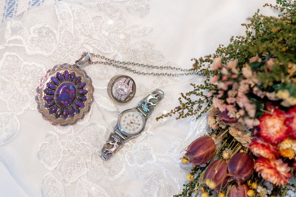 Native American silver jewelry collection with purple turquoise pendant, ring, and watch on white lace.
