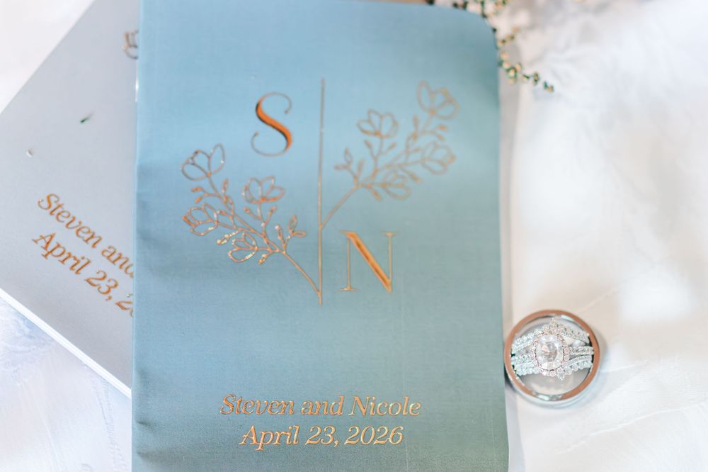 Sage green monogrammed wedding vow book with rose gold lettering and diamond ring beside it.