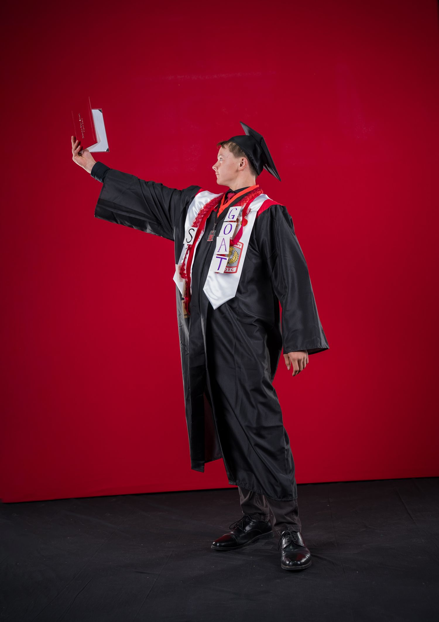 CHS graduate poses for 2025 Coconino High School commencement, covering his face during photos by Sean Openshaw Photography.