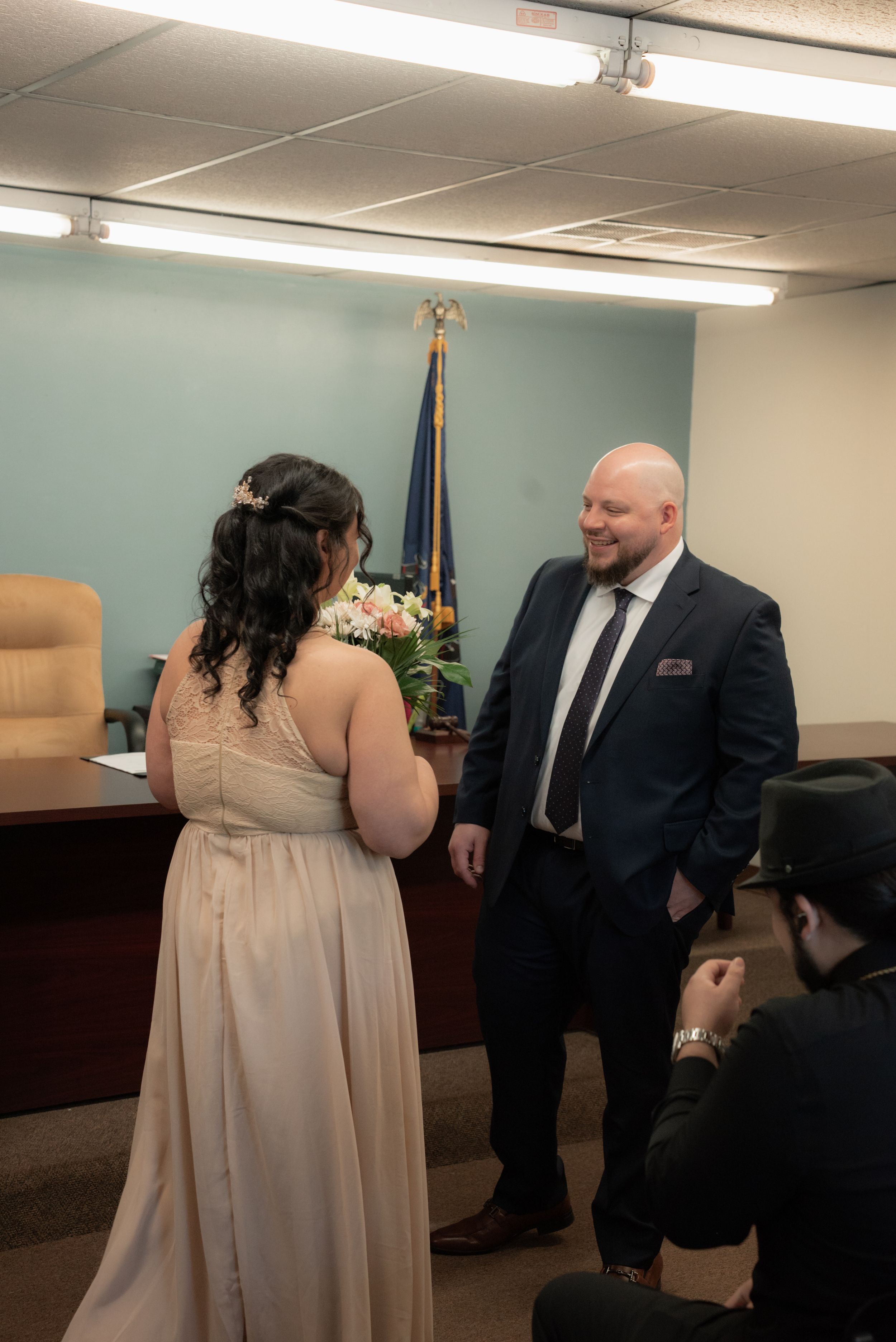 Couple exchanging vows at a courthouse wedding ceremony, bride in champagne gown, groom in navy suit.