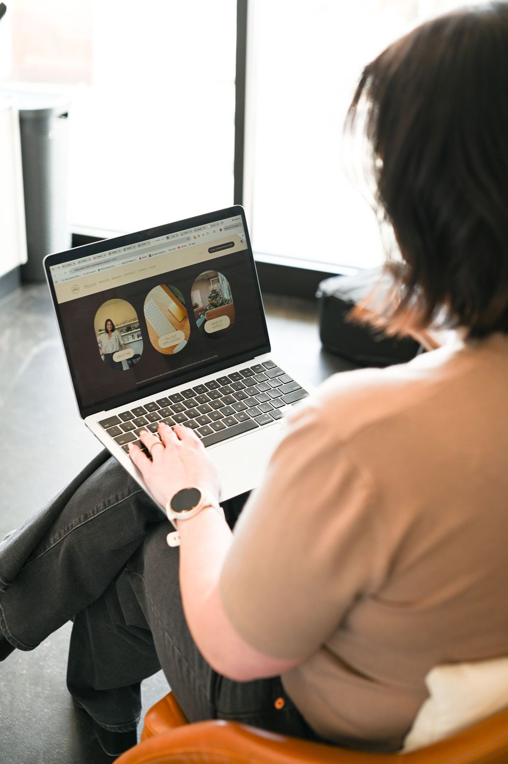 Woman working on laptop displaying website in bright modern space.