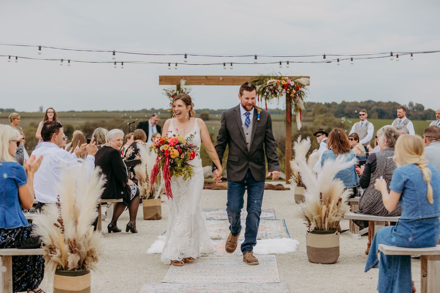 A newly married couple leaving their wedding ceremony and smiling at their guests in Dodge County, Wisconsin as bubbles float in the air.