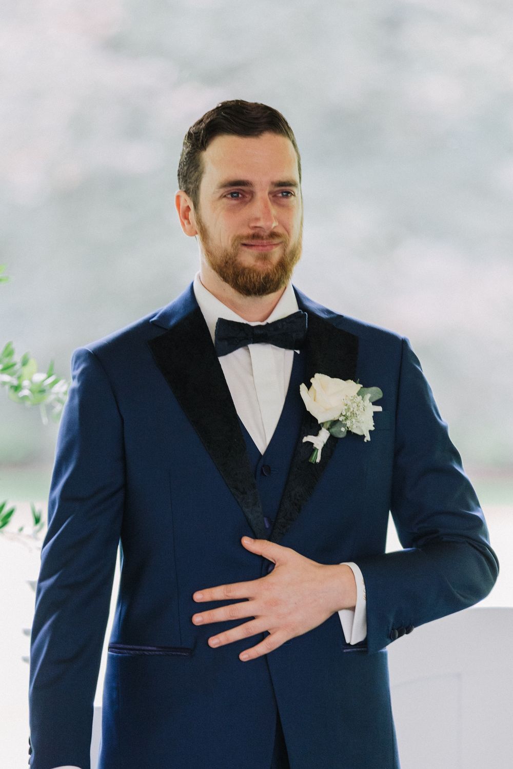 Groom in navy blue tuxedo shedding a tear upon the first look at the altar at wedding ceremony.