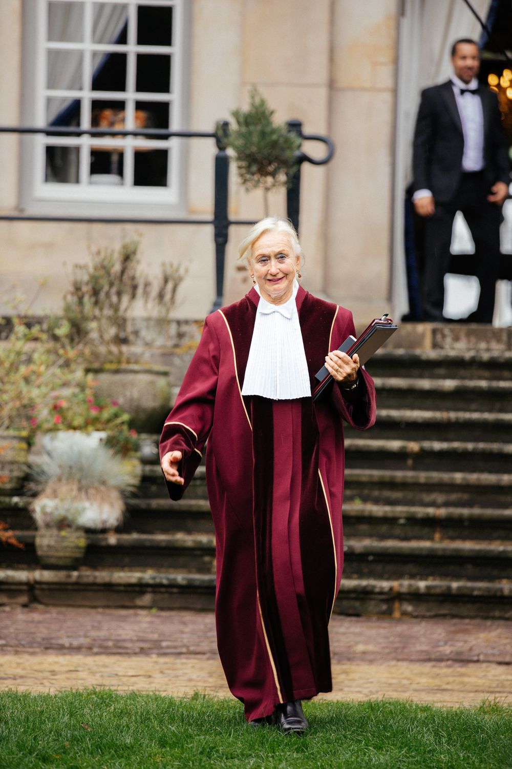 Wedding officiant walking gleefully down the mansion steps