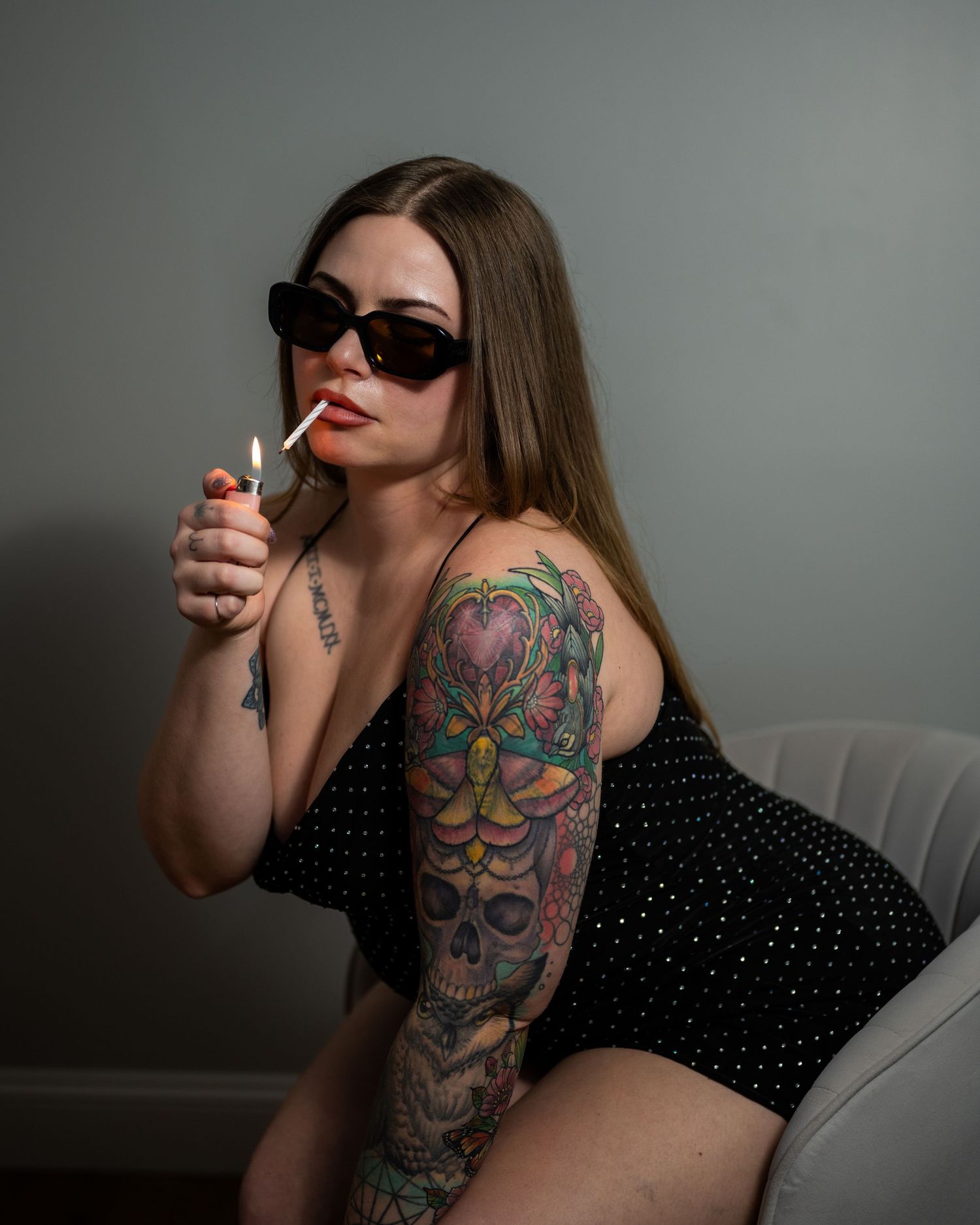 Woman with colorful sleeve tattoos lighting a candle as a fake cigerette. These are her birthday portrait photos.
