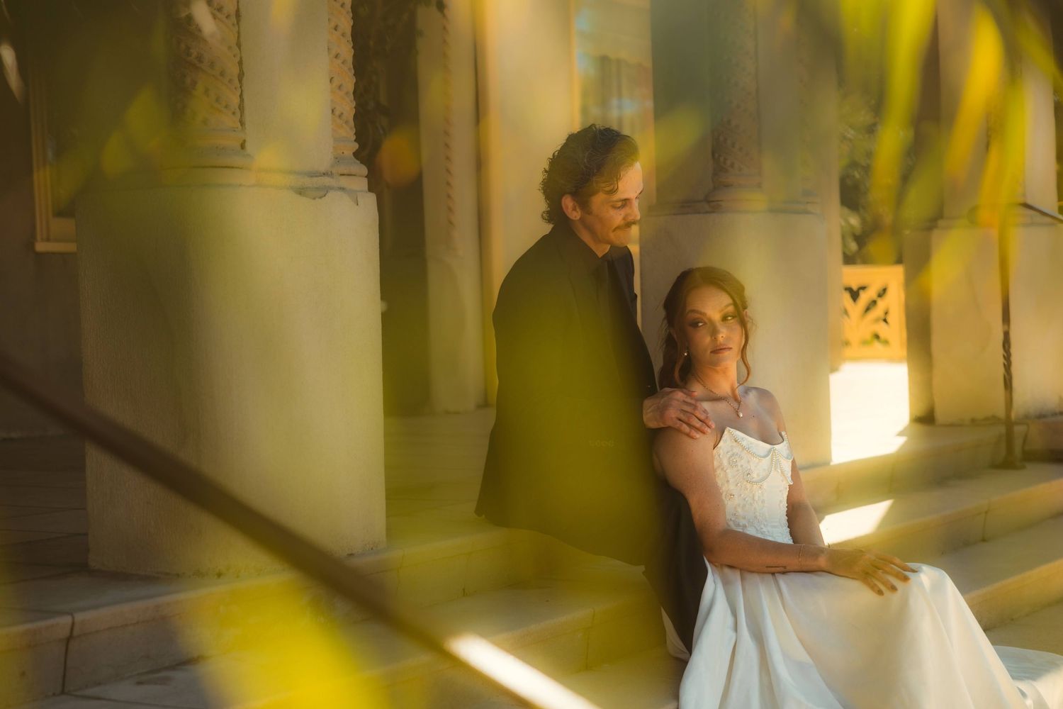 Bride in white gown holding bouquet stands with groom in black suit on the grounds of the Kimberly Crest House wedding venue.