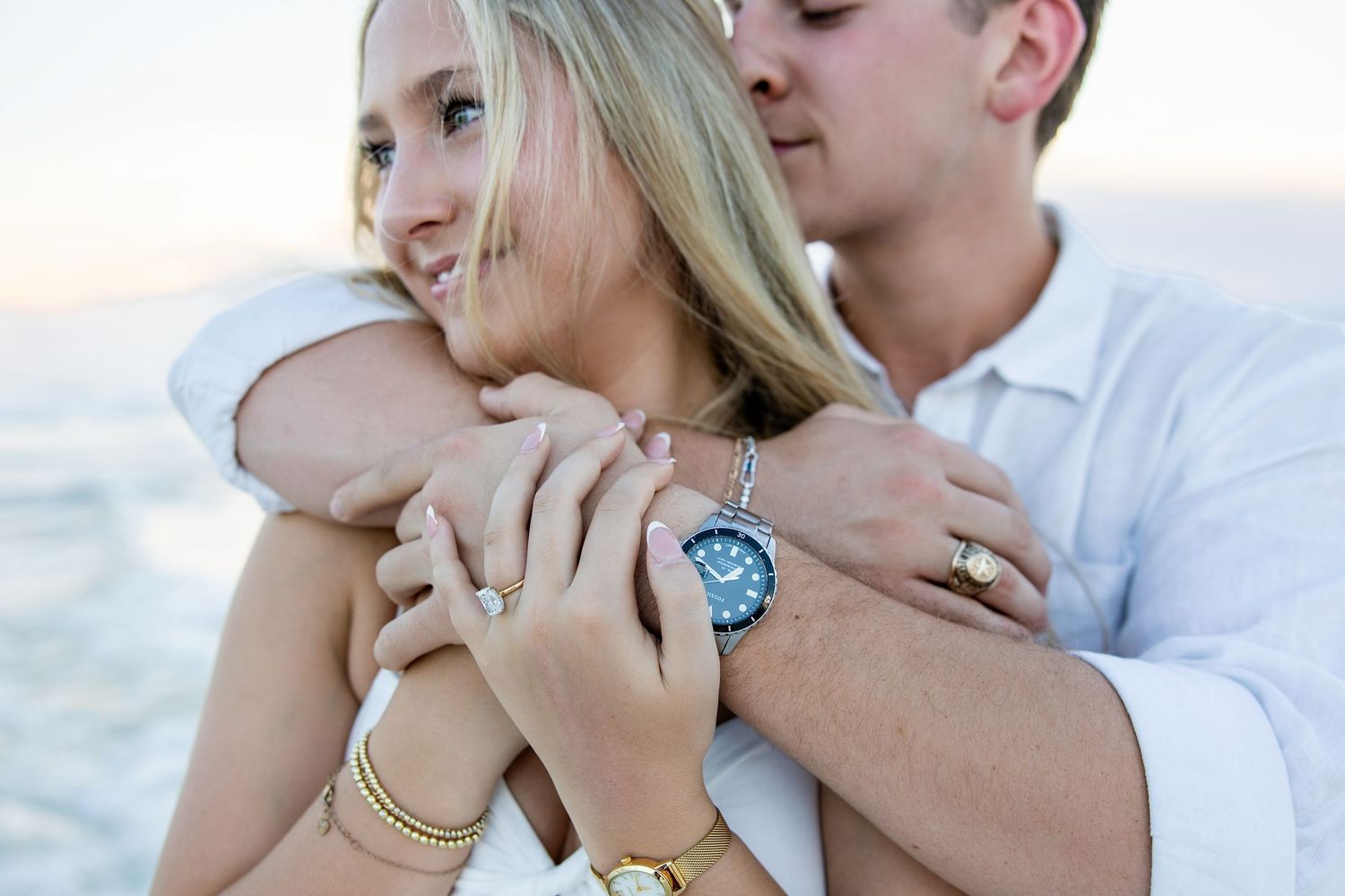 newly engaged couple cuddling on the beach