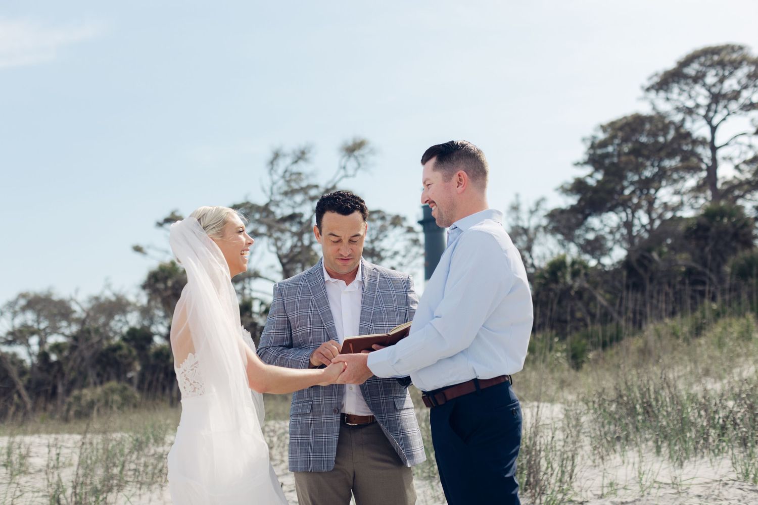 Bride and groom walking along a serene beach shoreline on their wedding day, with ocean waves in the background.