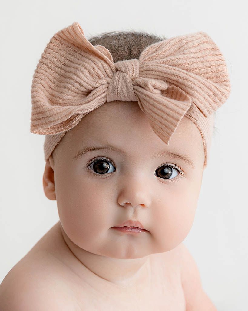 Adorable baby girl with big blue eyes wearing a blush pink ribbed bow headband.