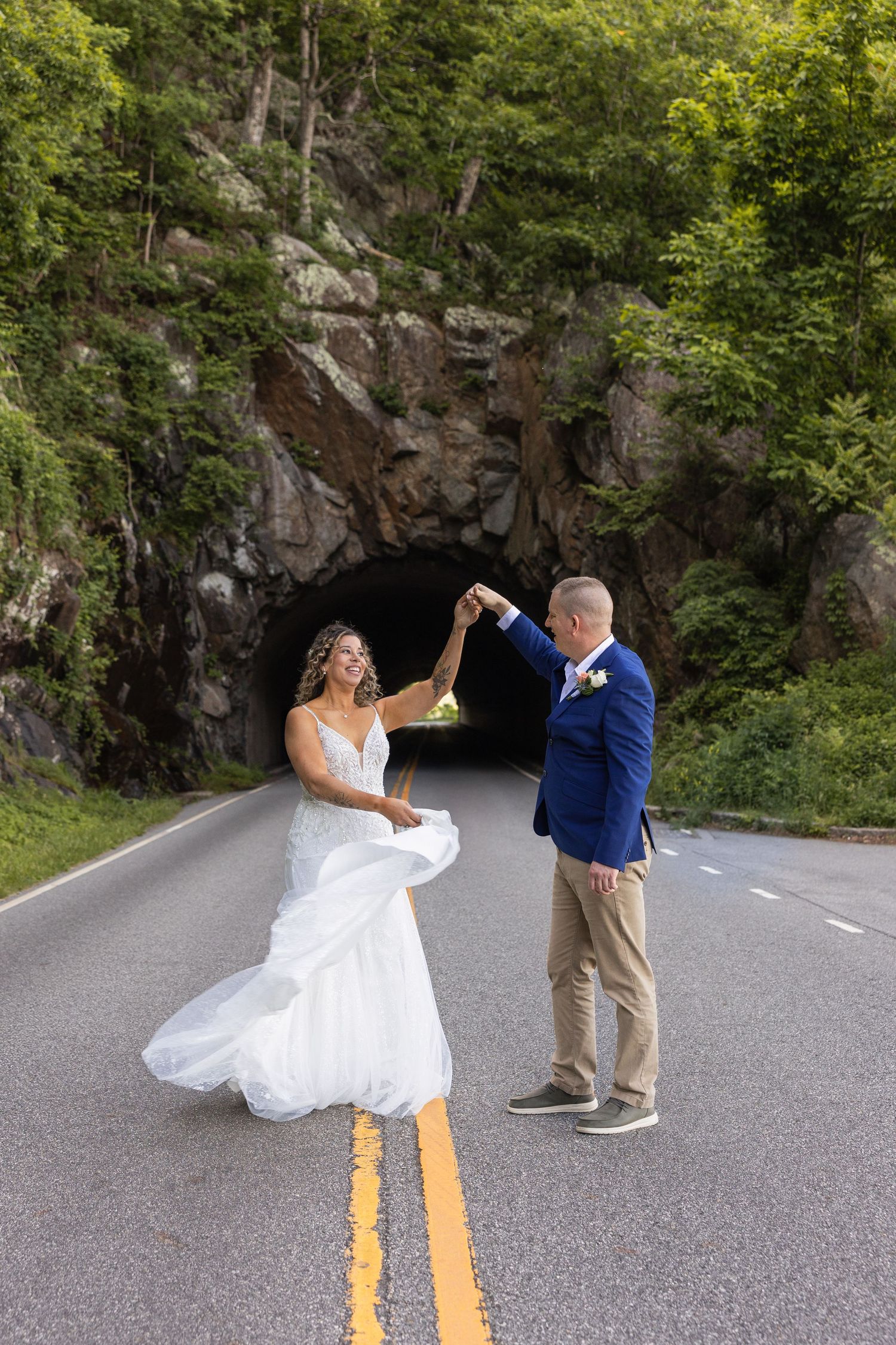 Bride and groom dancing on a road in front of Mary's Rock Tunnel in Shenandoah National Park on their elopement day.