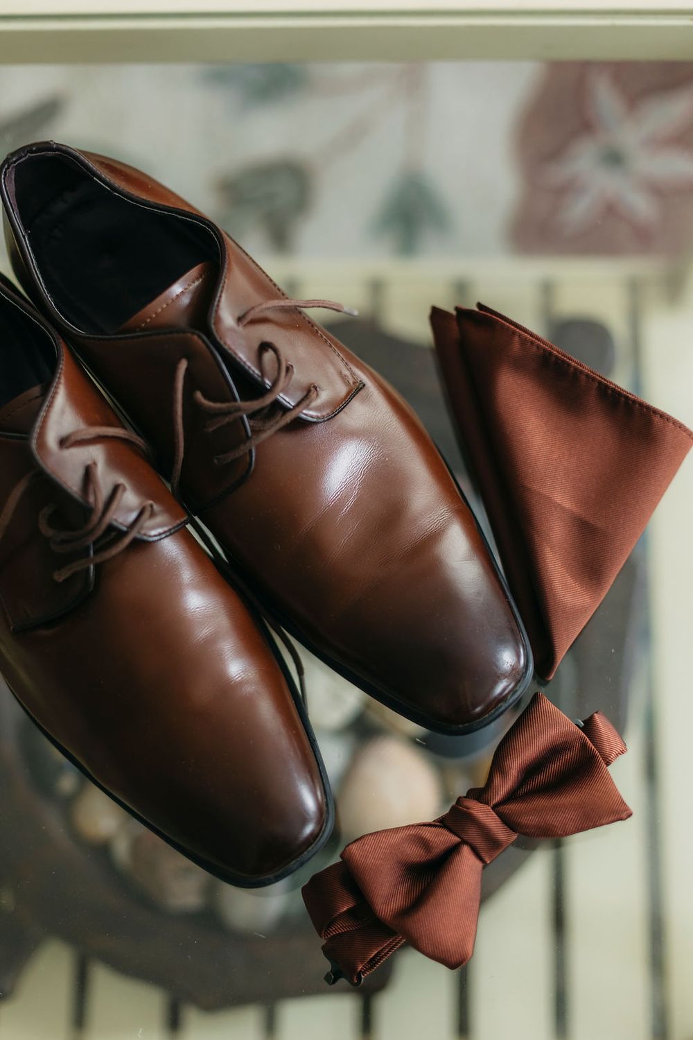 Brown leather dress shoes with matching brown bow tie and pocket square arranged elegantly for a wedding in Chicago