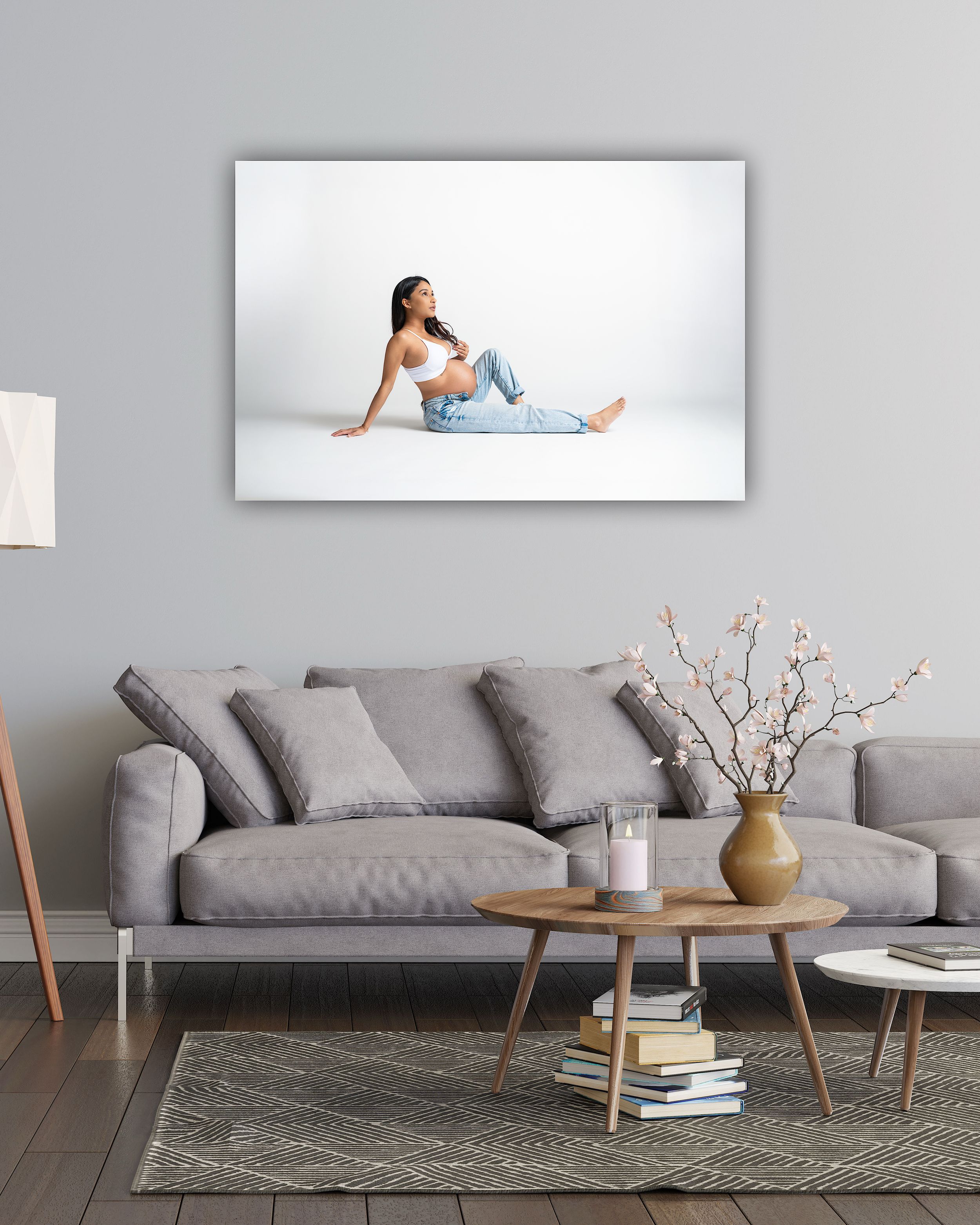 A woman in jeans and a white top sits gracefully on the floor in a modern living room wall art display.