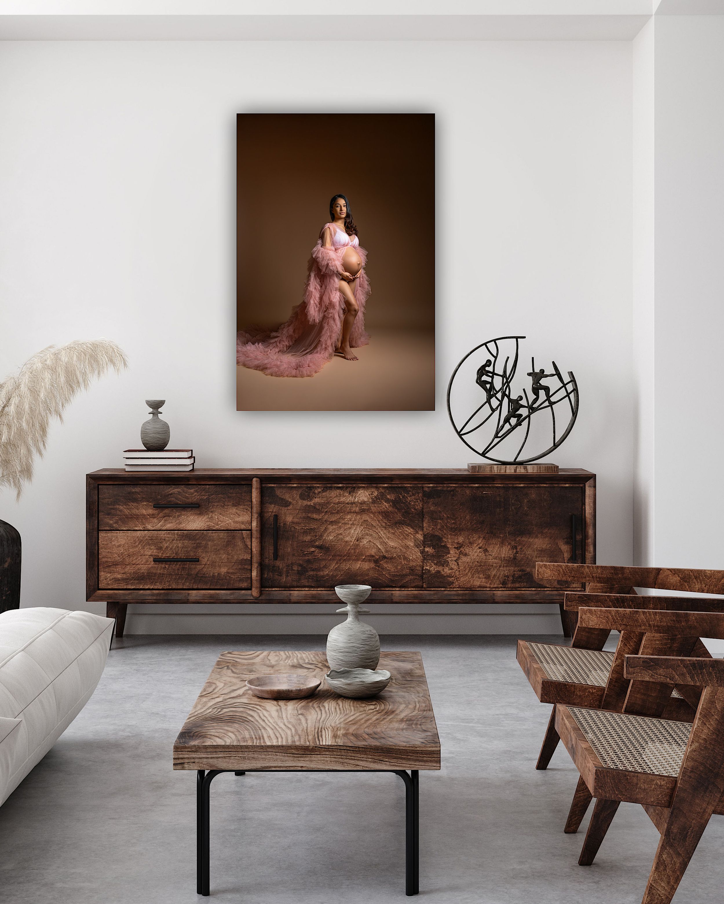 Elegant living room with warm wood furniture, a maternity portrait canvas, sculptural decor, and neutral tones.