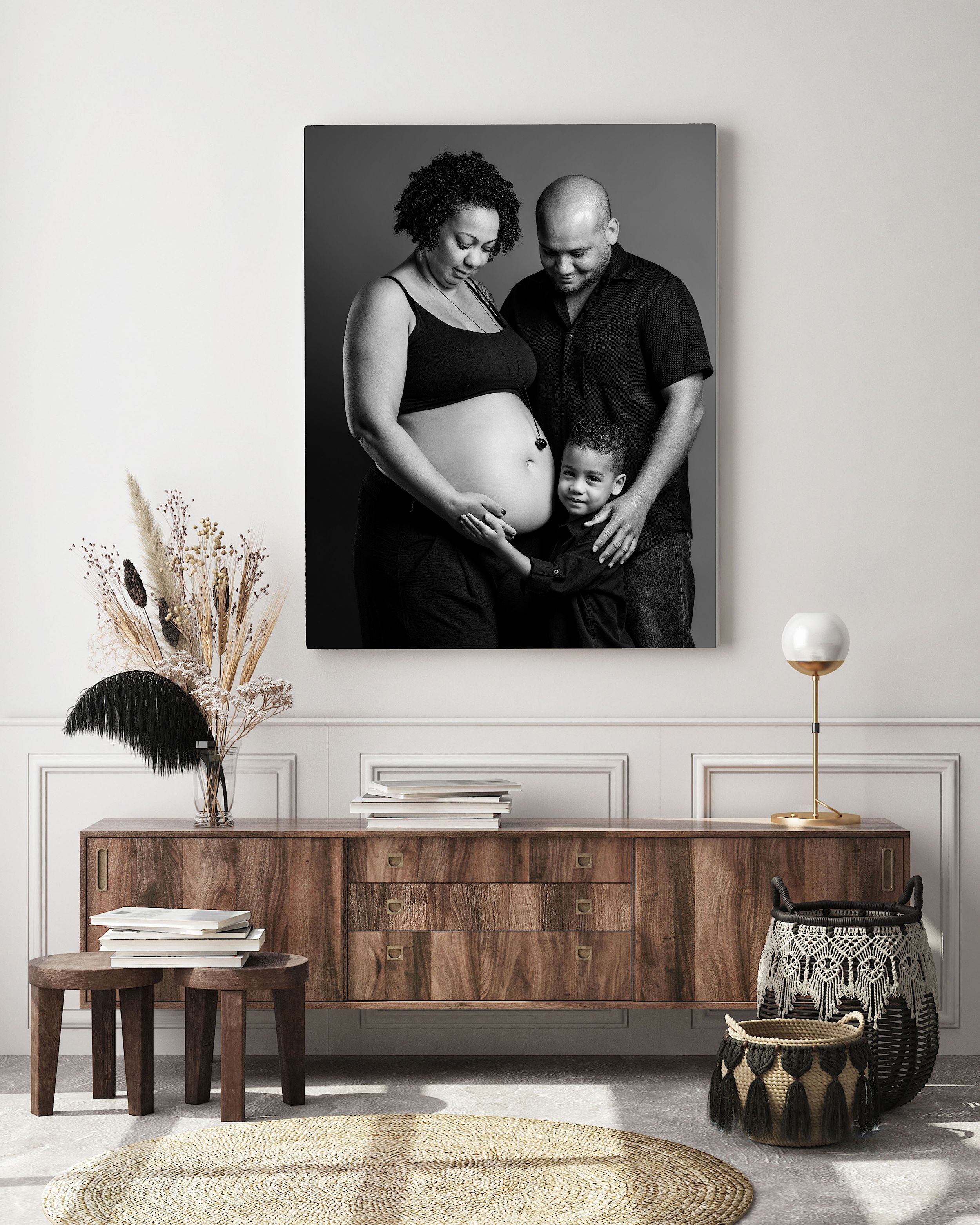Black and white maternity photo canvas print displayed above a wooden sideboard in a modern living room.