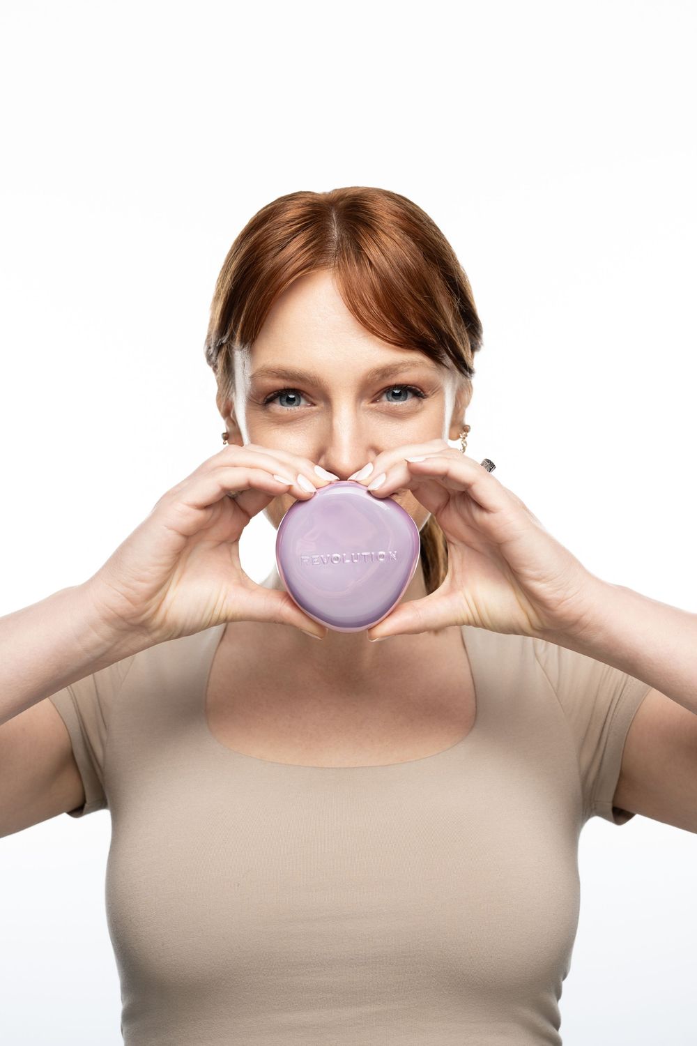 Woman holding a purple heart-shaped box up to her face, smiling with bright eyes against a white background.
