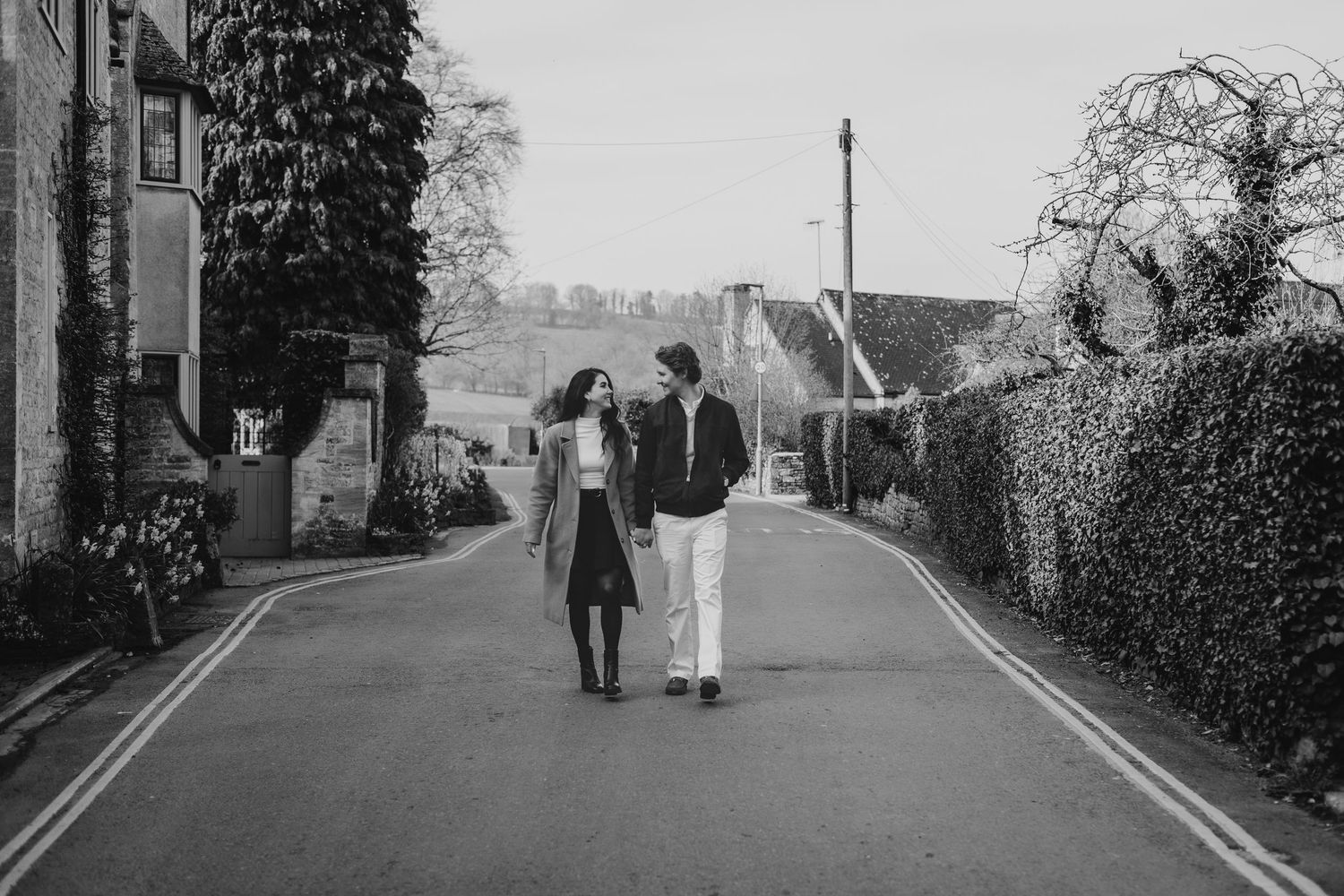 Couple walking together on a quiet village in the cotswolds in black and white photography.