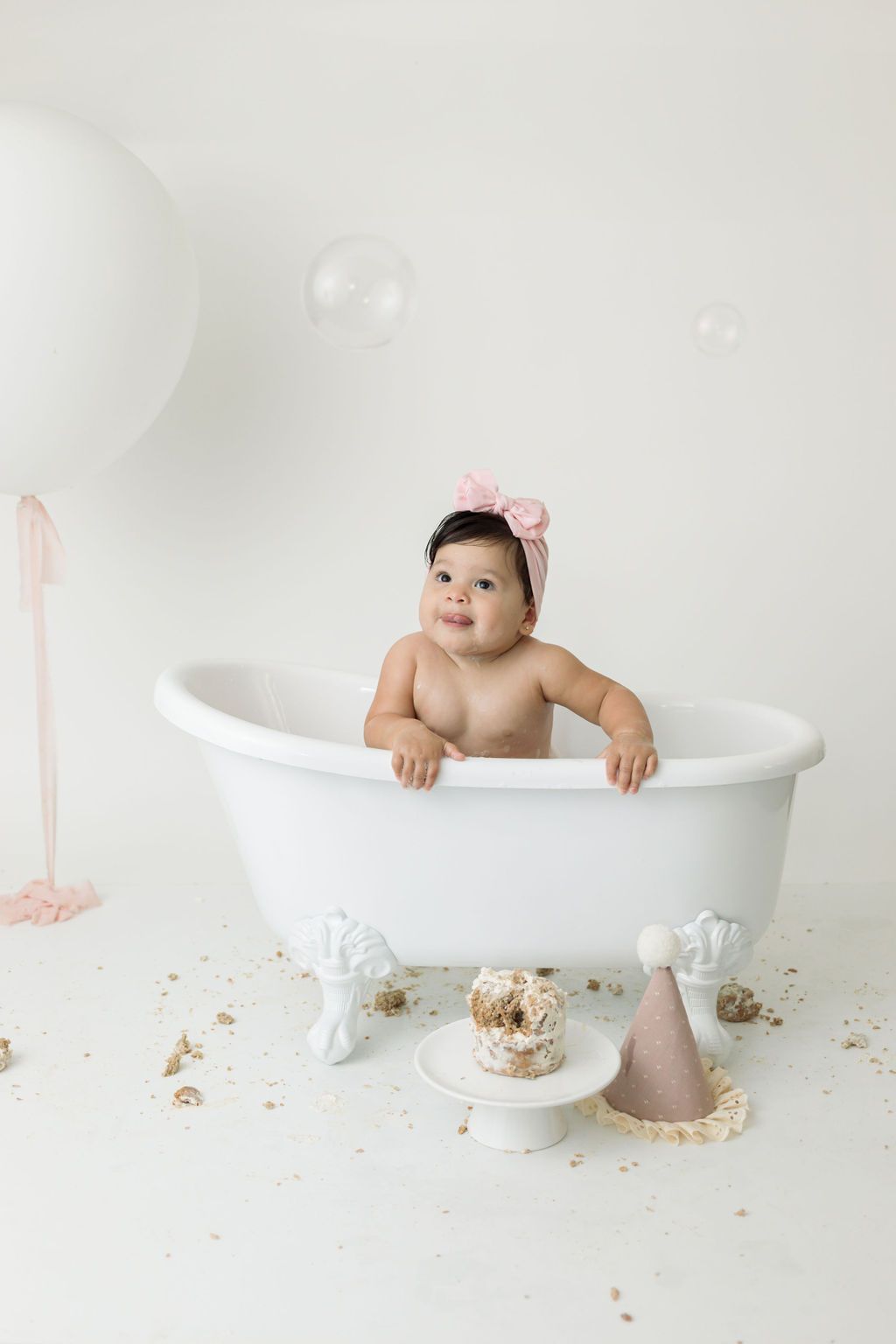 Bath time setup with white tub, balloons, and smash cake.
