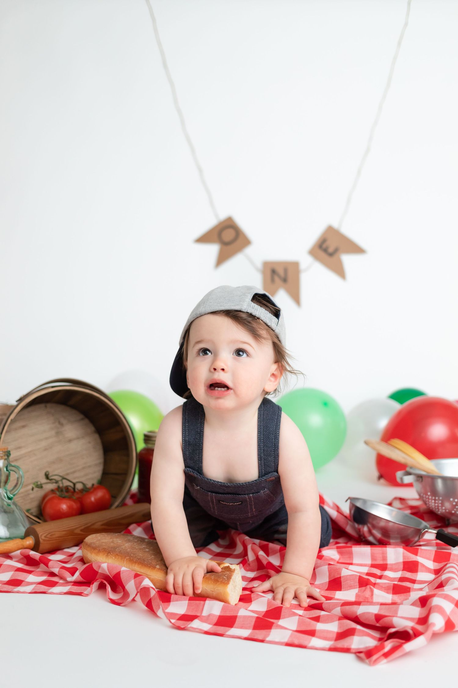 Picnic themed birthday setup with red checkered blanket, wooden barrel and colorful balloons.