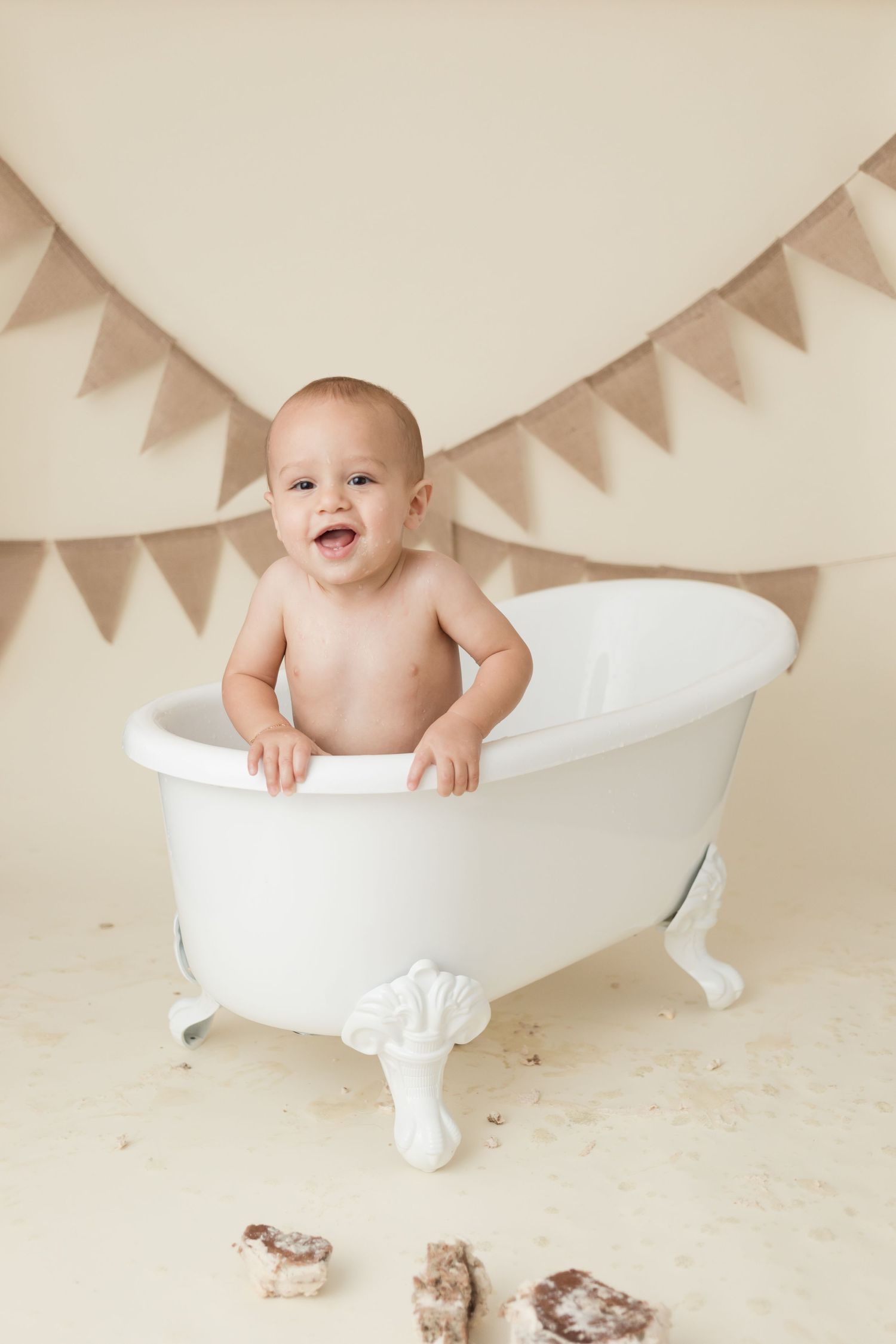 A vintage-style white clawfoot bathtub with bunting decorations for a milestone photo session.