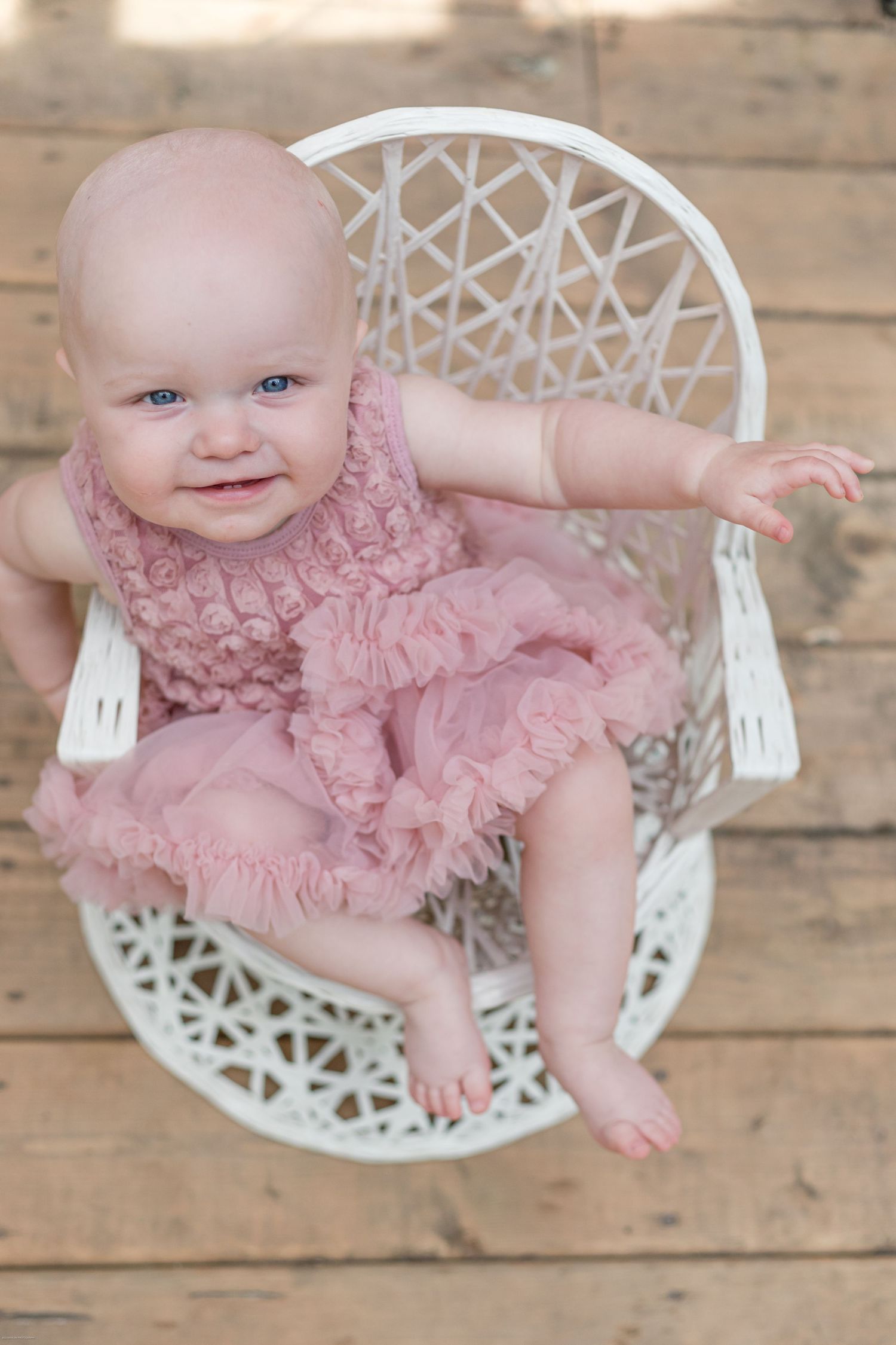White wicker chair with lace pattern on wooden floor background.