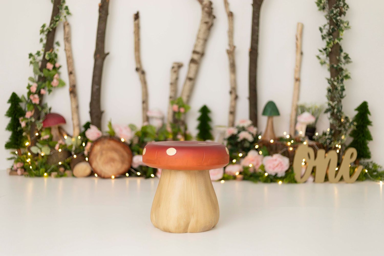 Decorative woodland scene with wooden mushroom, twigs, and fairy lights against white background.