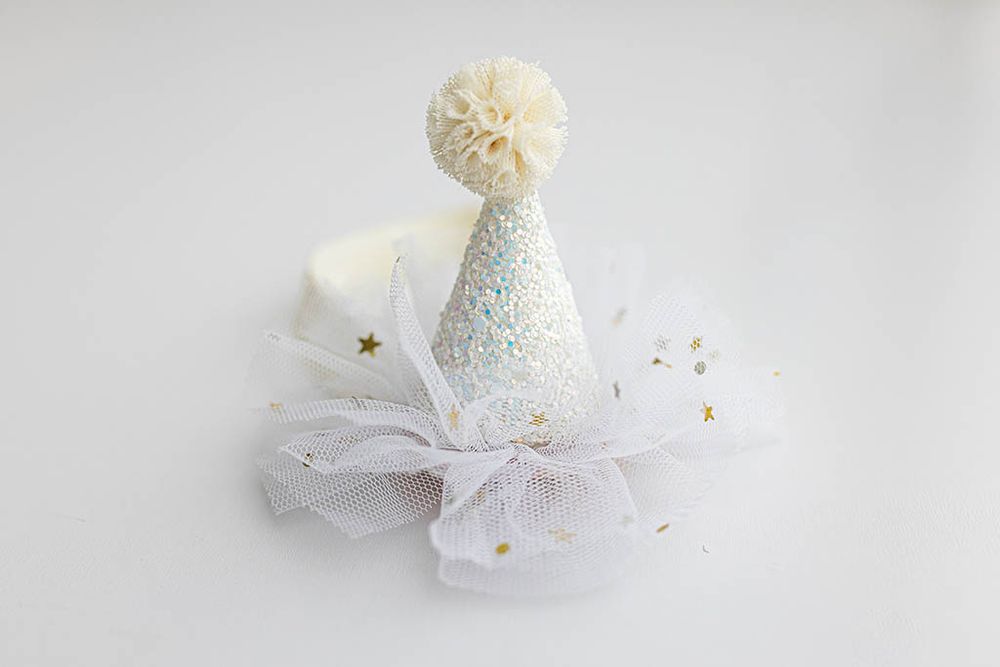 White iridescent glitter party hat for baby photos.