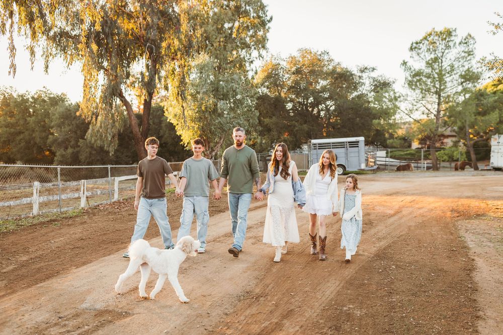 Family walks together on a dirt path with a white dog at blooming ridge ranch