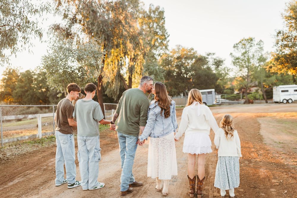 Family holding hands walking down a sunny dirt at a ranch in cherry valley ca