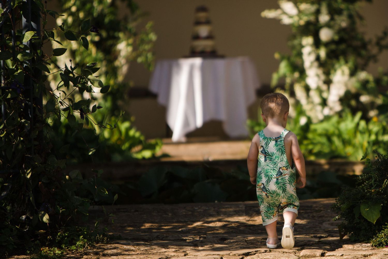Bride and groom walking in green field, swinging children by hands, golden hour wedding photo.