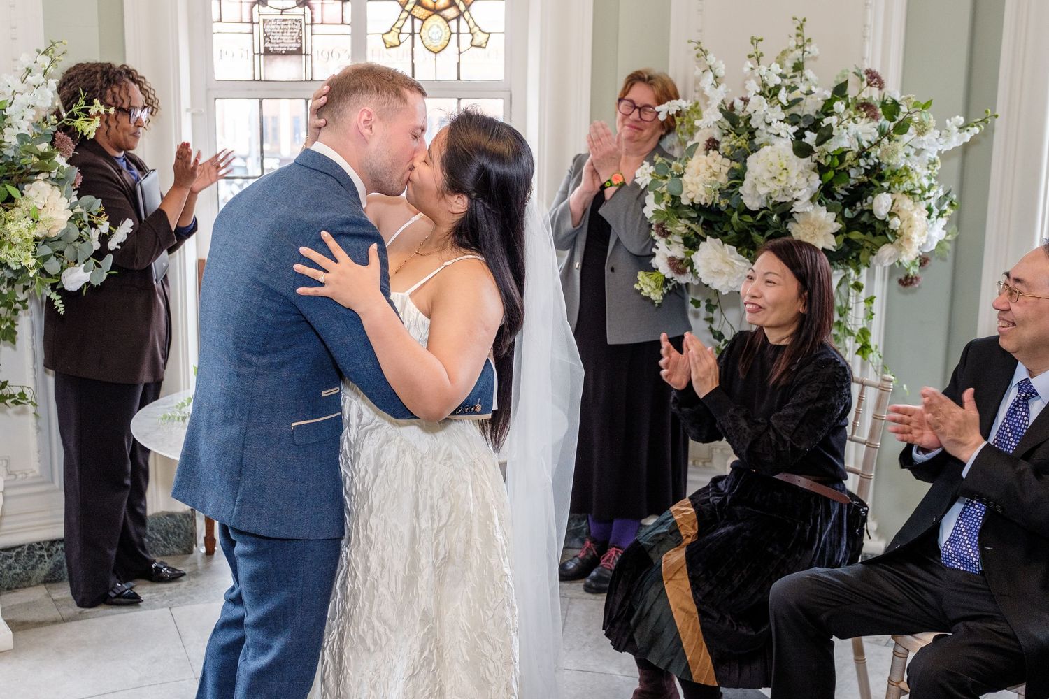 A couple in wedding attire walks together through a lush garden setting during their Islington ceremony.