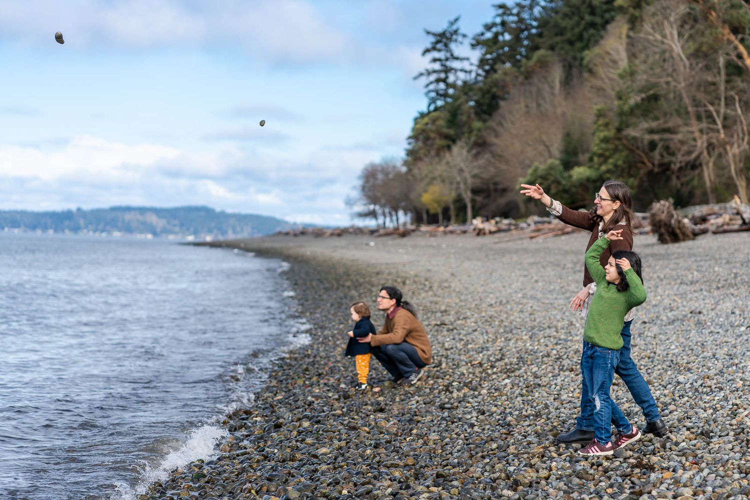 Mom and child throwing rocks while father and child look on in the distance.