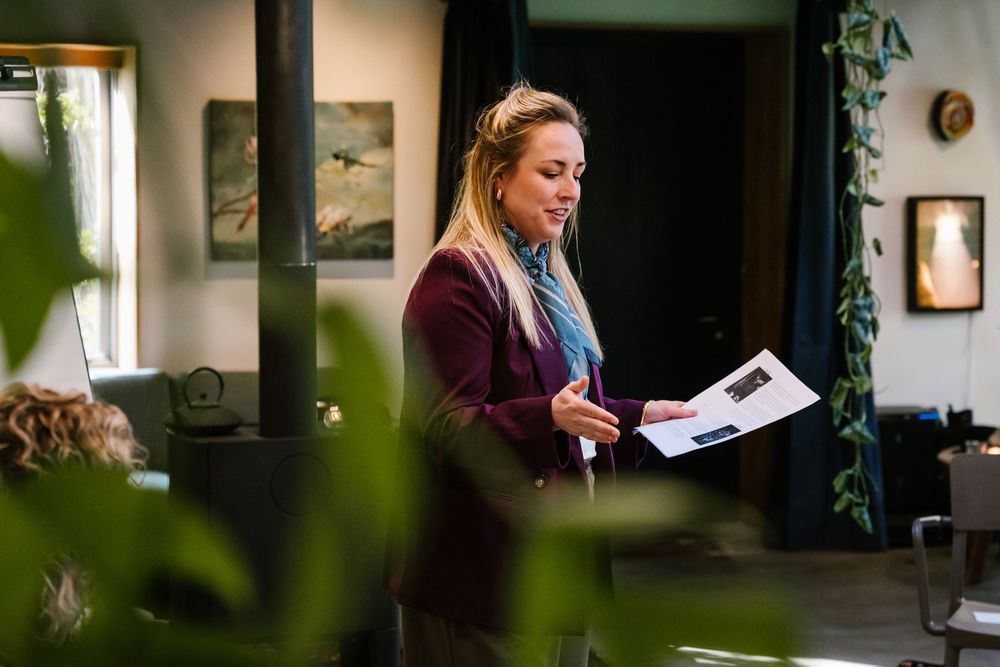 Woman in burgundy blazer reviewing documents in a stylish art-filled interior space.