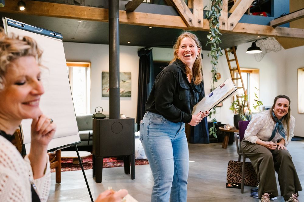 Three women laughing and collaborating in a modern studio space during a creative workshop session.