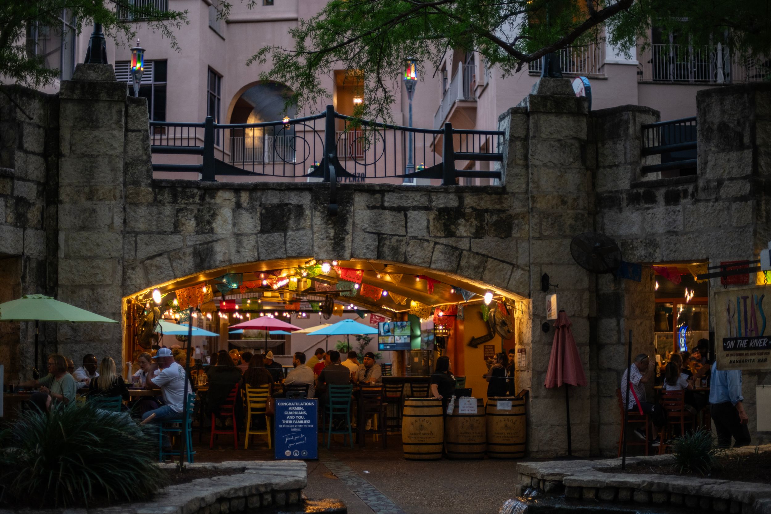 Colorful illuminated archway entrance to a lively outdoor restaurant patio at dusk in San Antonio.