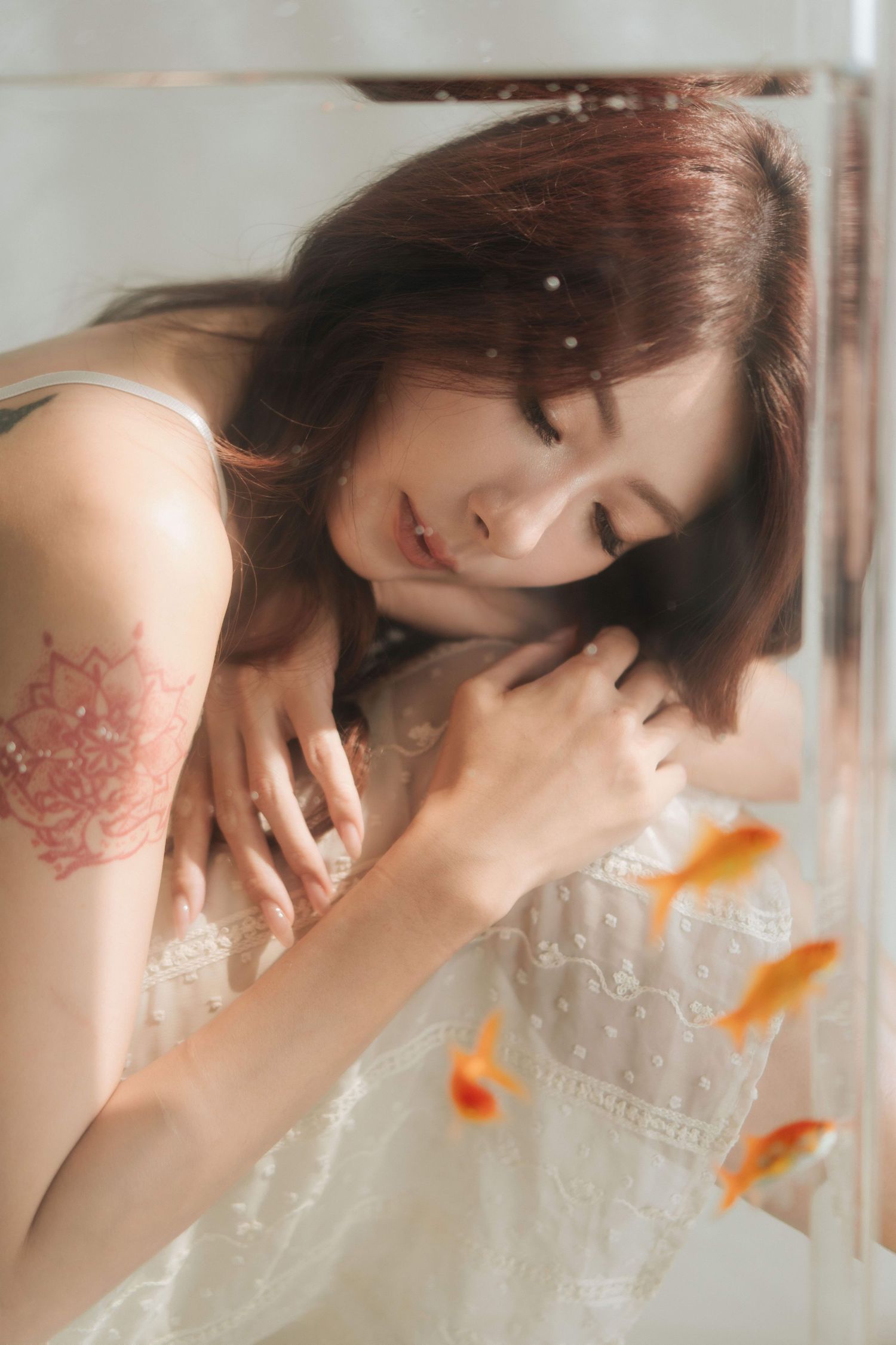 Side portrait showing delicate dangling earrings and elegant lace dress details in soft lighting.