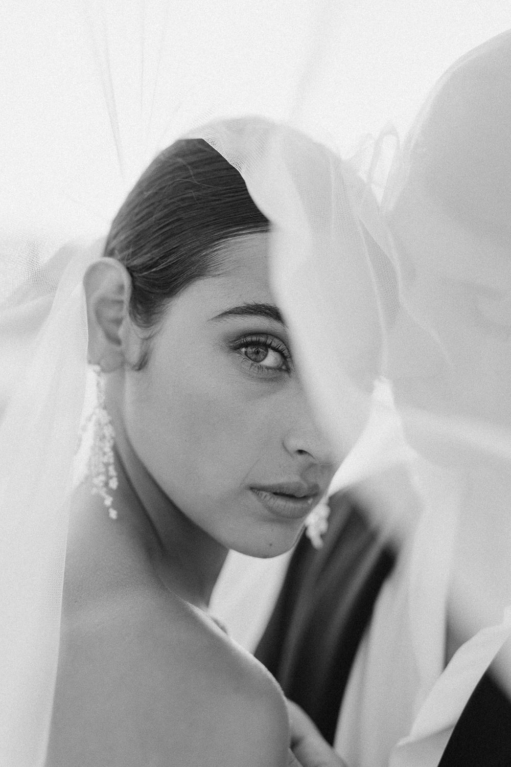 Black and white bridal portrait of a woman in a veil with pearl earrings, elegant wedding photography in Malta.