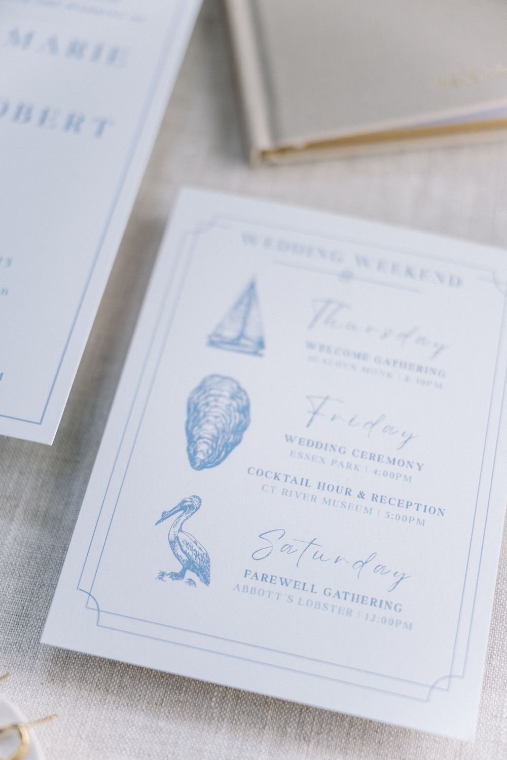 Nautical-themed wedding weekend itinerary card with blue illustrations of sailboat, oyster, and pelican.