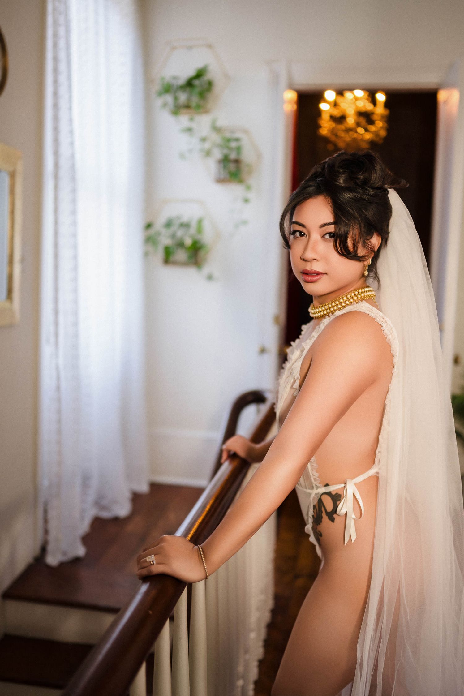 Bride in lingerie and veil with gold jewelry poses elegantly on staircase in vintage interior. bridal boudoir photoshoot