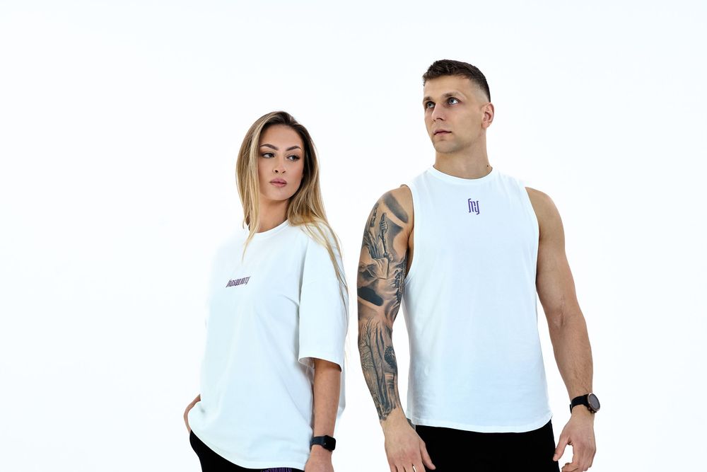 A man and woman wearing white athletic wear pose against a white background, showcasing casual fitness apparel.