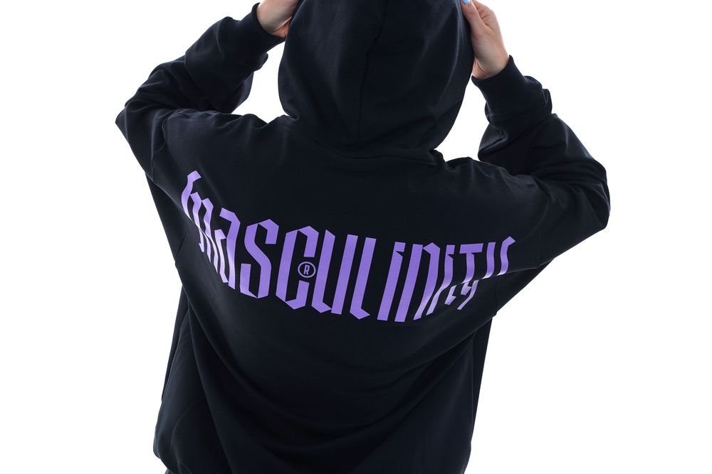 Black hoodie with purple Masculinity logo text on the back, worn by a model with hands raised to hood.