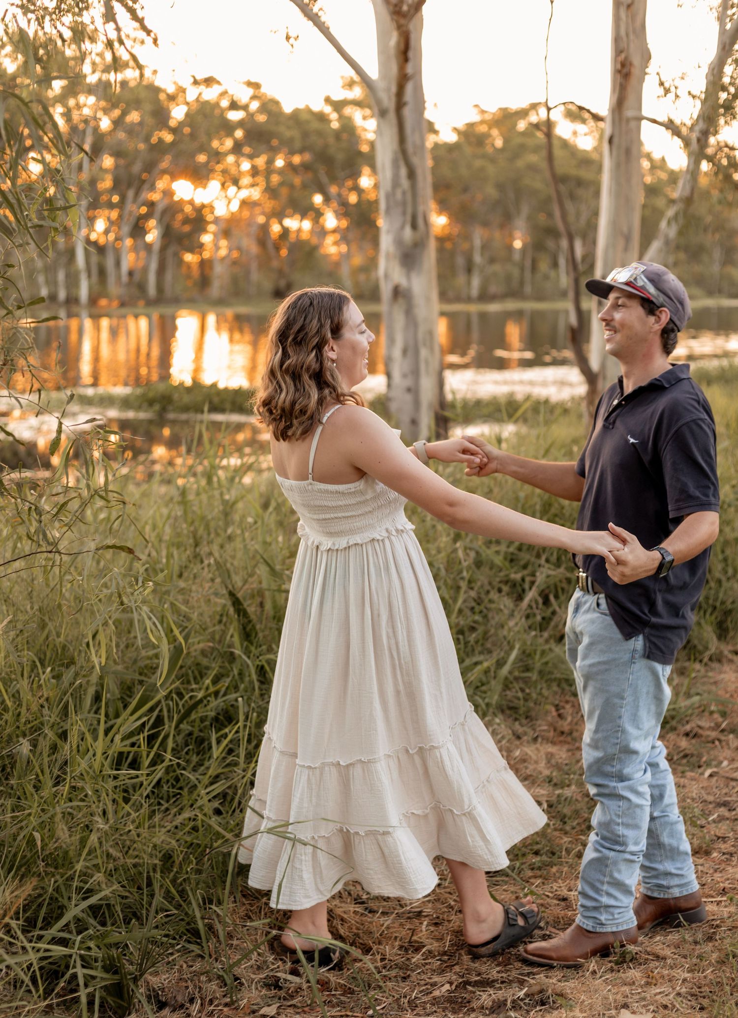 Couple dancing at golden hour near a tranquil lake surrounded by eucalyptus trees in Australia.
