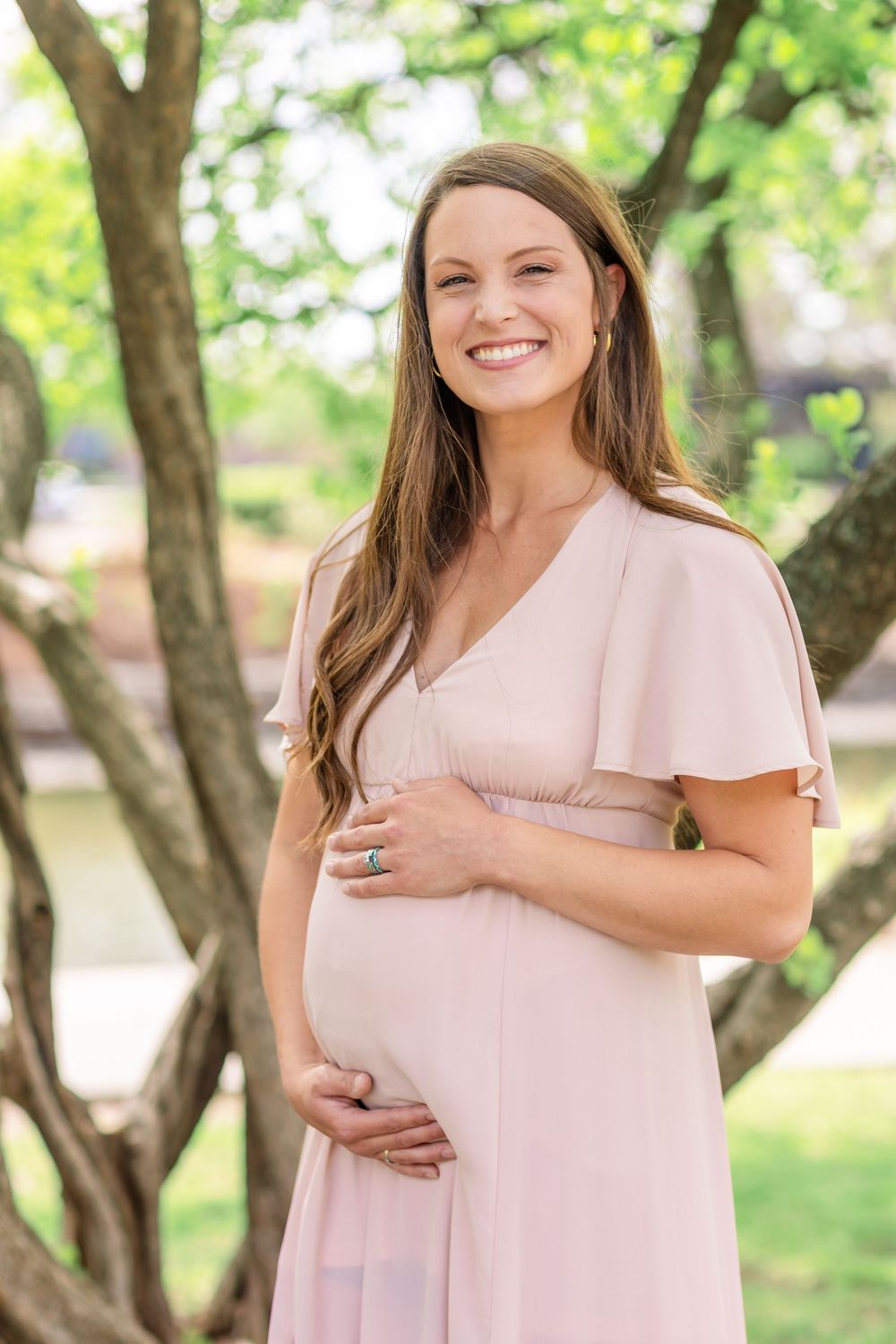 Spring maternity session in Wichita, Kansas with blooming trees and golden morning light